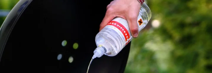 Person gießt Grillanzünder in Grill
